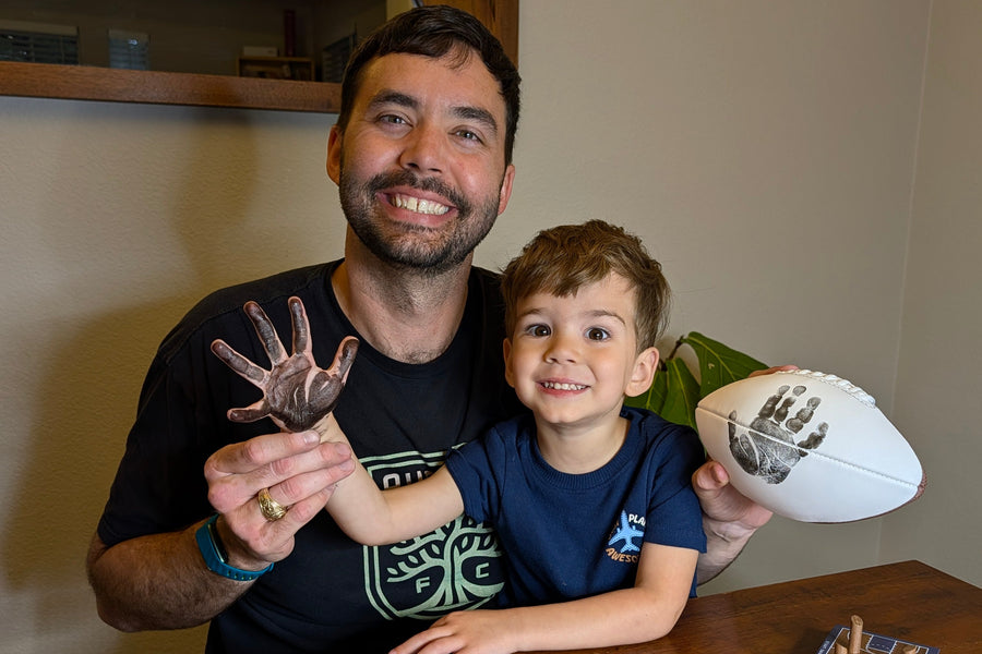 Man and Childing making ink handprint keepsake memory with sports balls